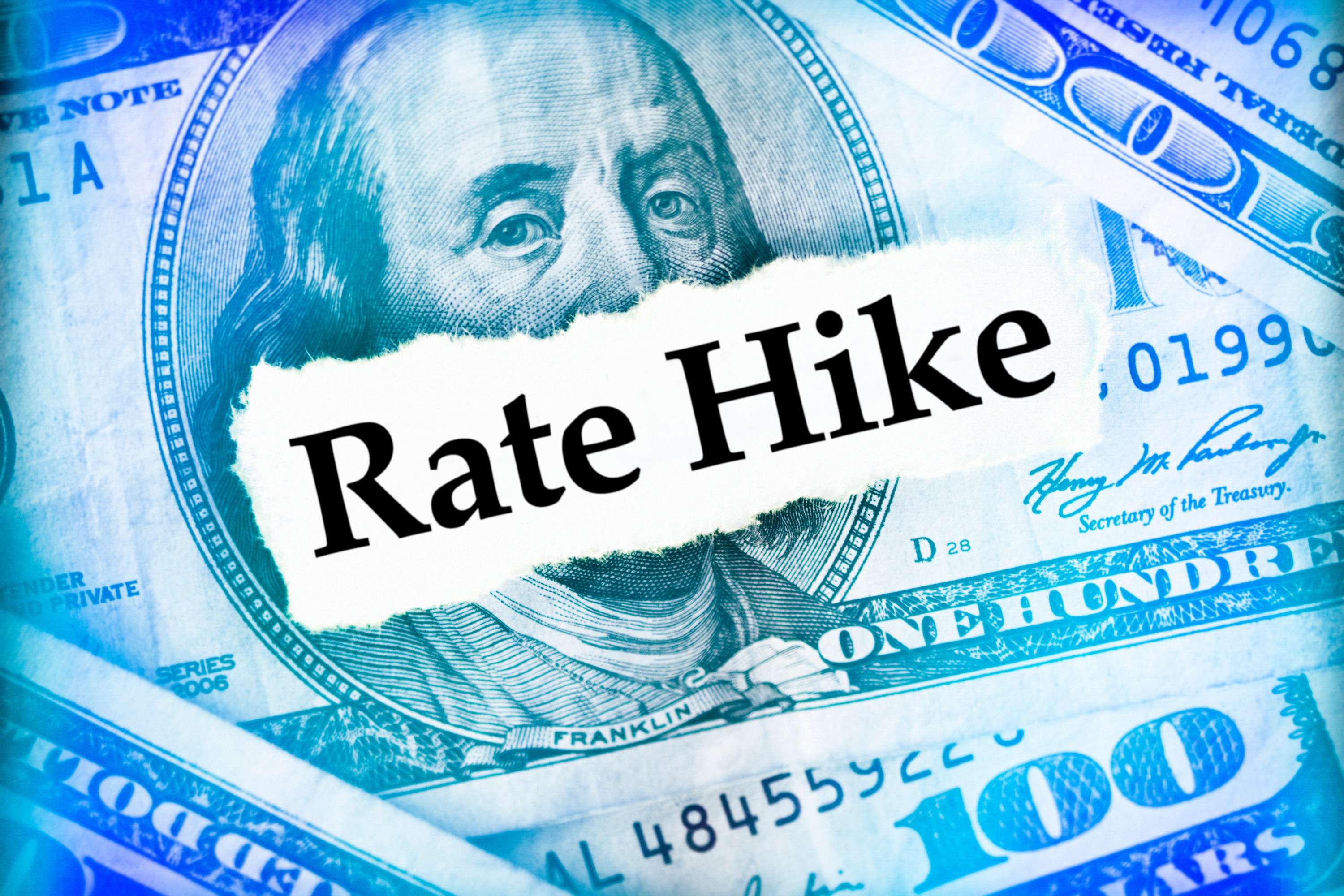 The words "Rate Hike" superimposed over several $100 bills.