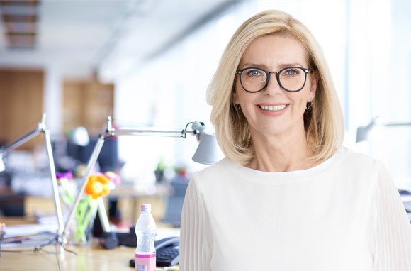 A smiling person in front of a desk.