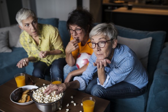 Friends sharing popcorn on the TV couch.