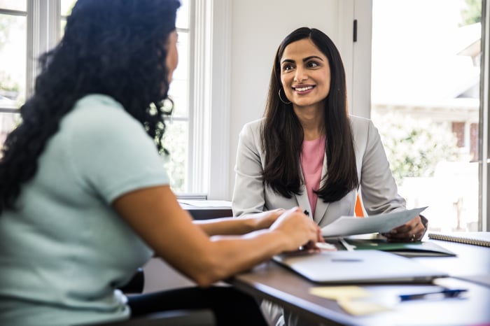 Two people discussing paperwork in an office.