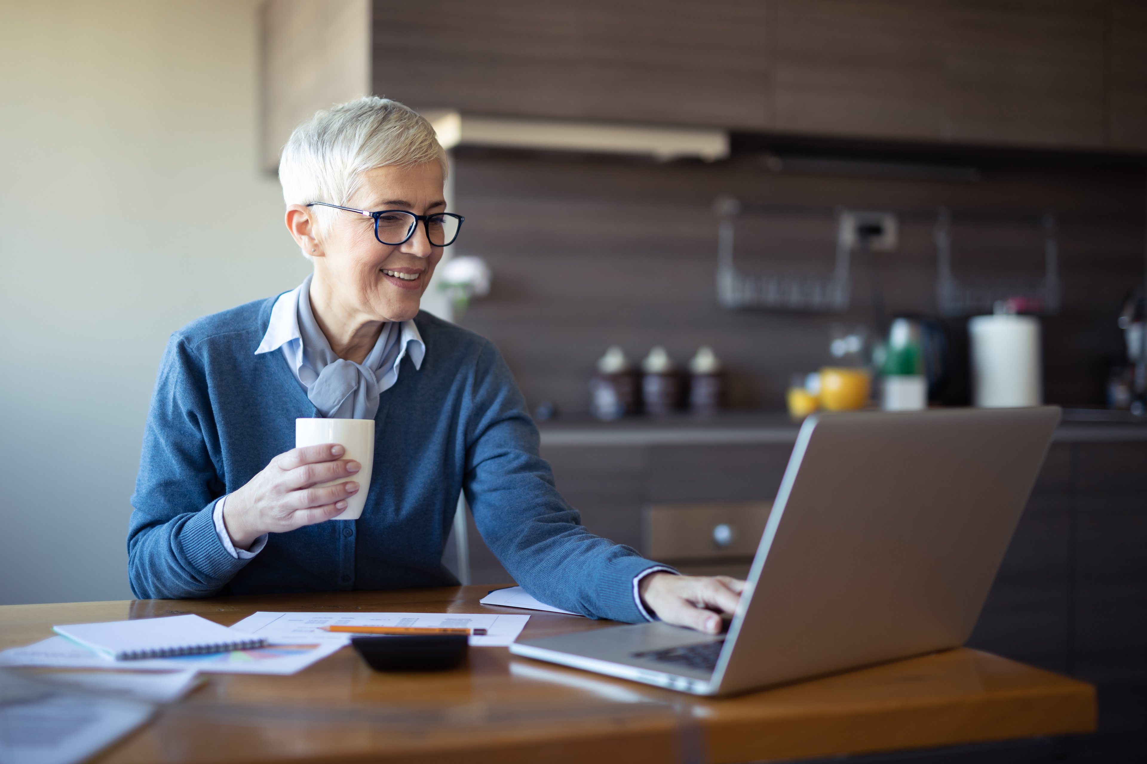Person in kitchen looking at laptop.