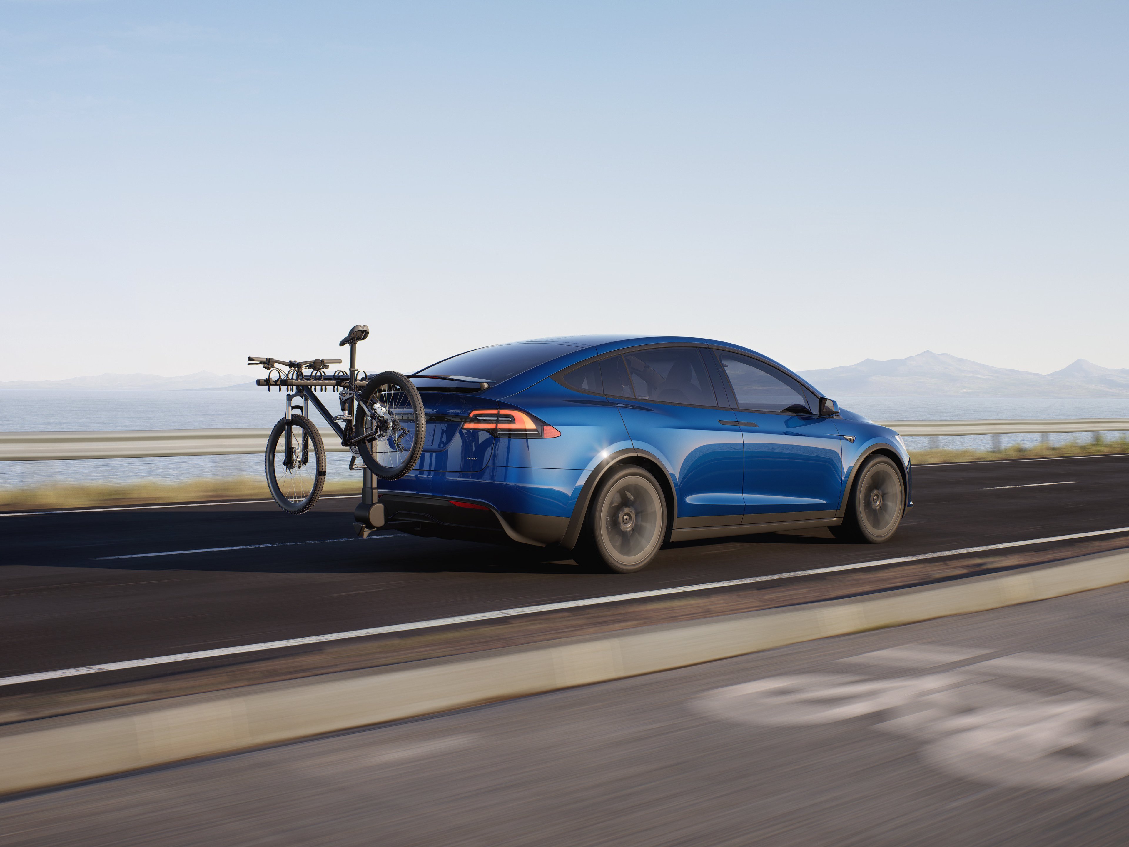 Blue Tesla Model X with bicycle on back rack. 