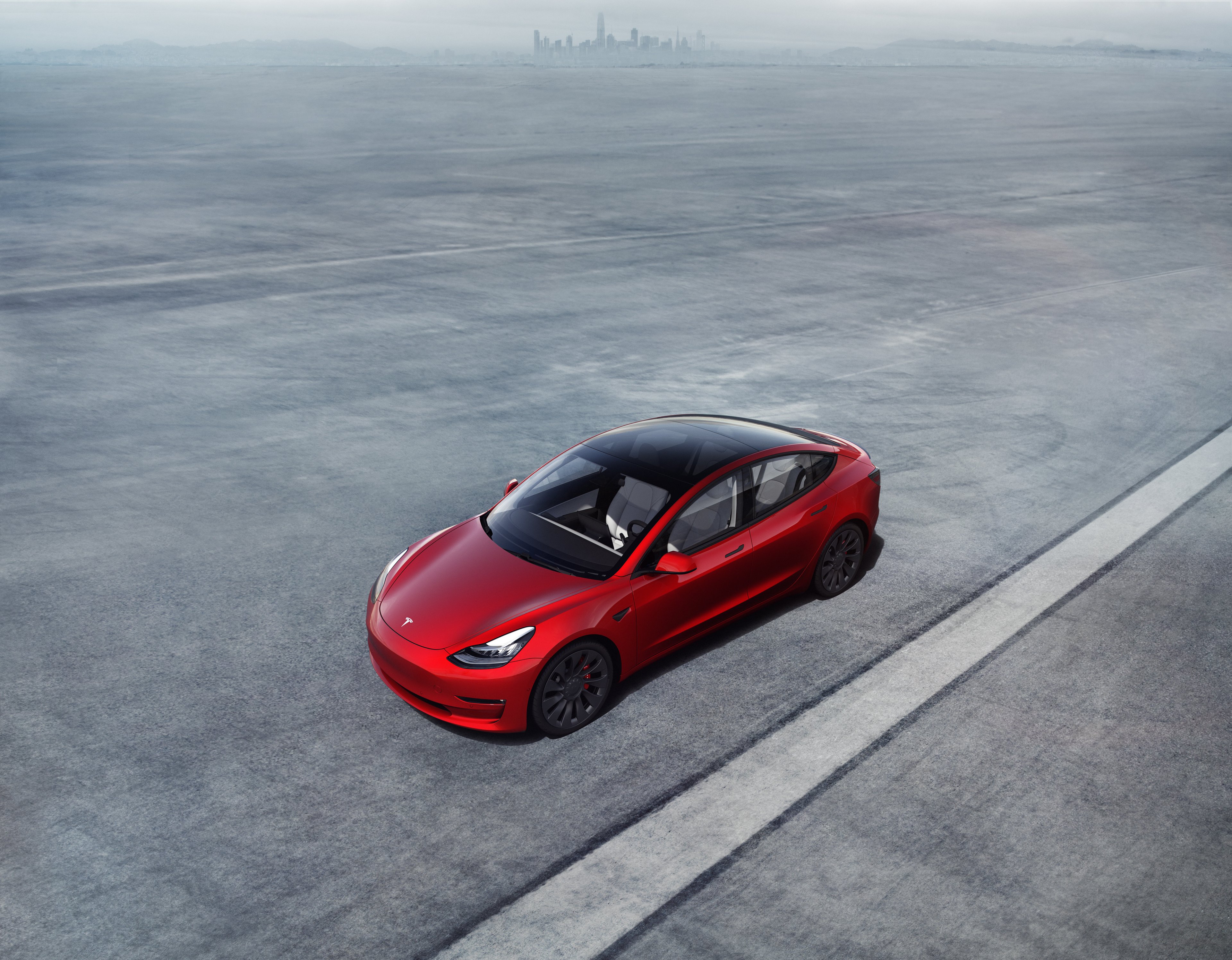 A Tesla Model 3 speeding along a deserted road. 