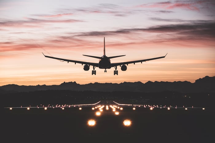 Silhouette of a plane taking off from a runway at dusk. 