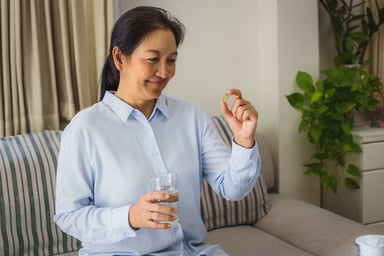 Asian woman holding a pill