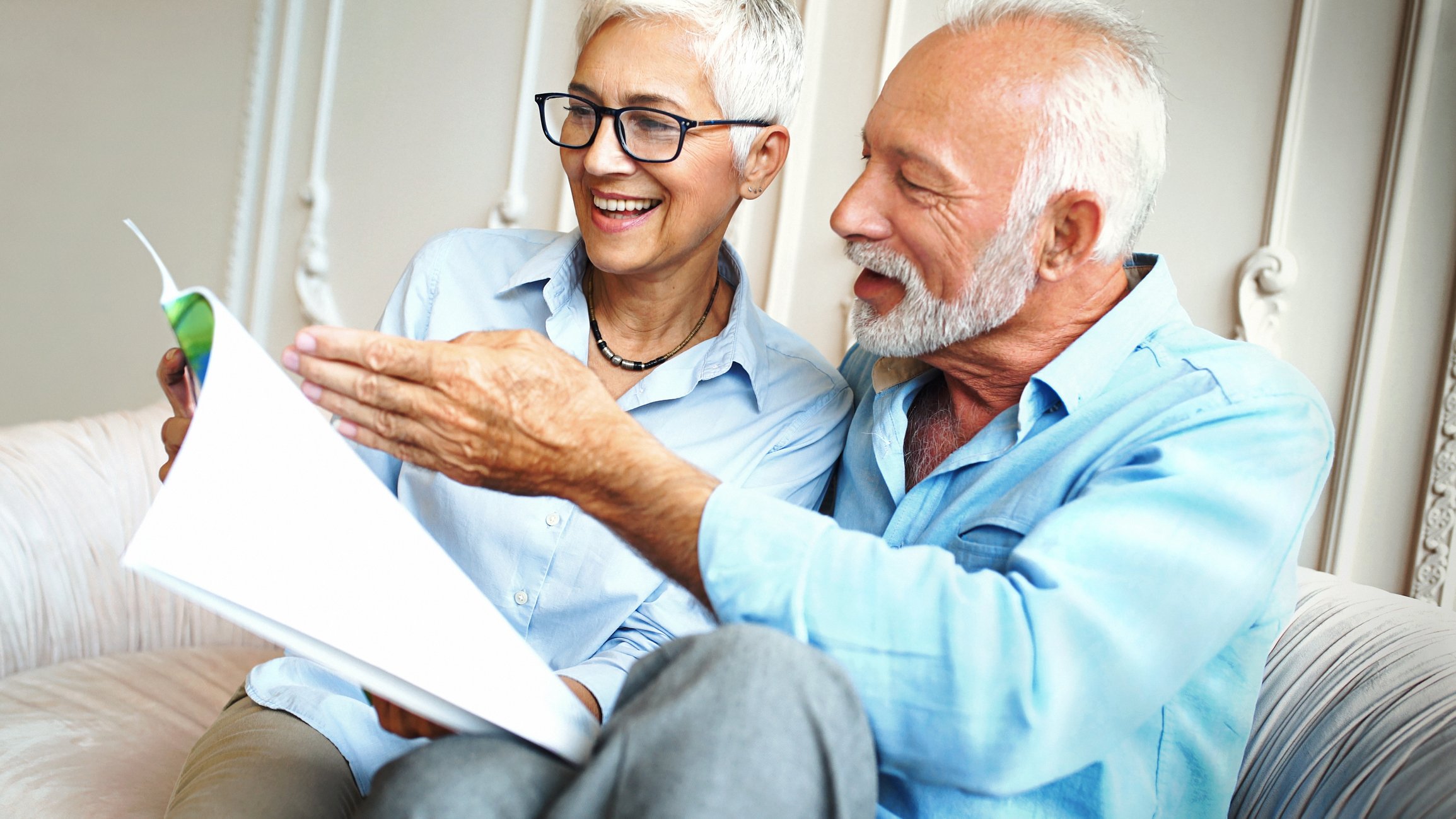 A couple discussing financial documents while seated on a couch.