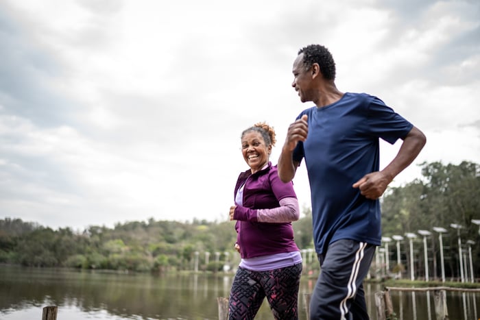 Two people jogging in front of a lake.