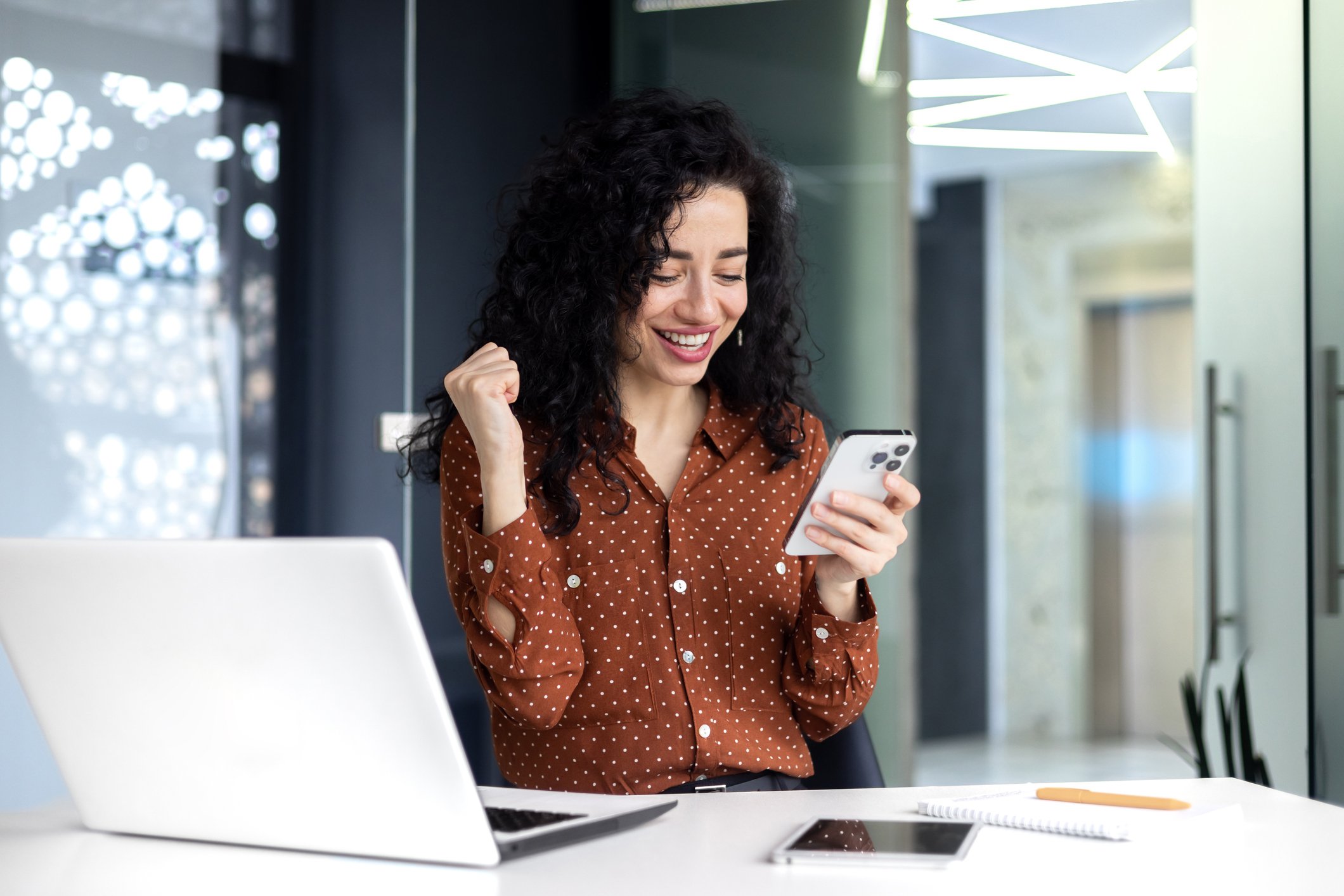 An investors looks at a smartphone and celebrates.