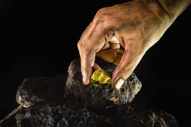 Miner picks up gold nugget from dirty ore