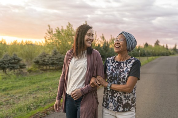Two people walking arm-in-arm on a country road.