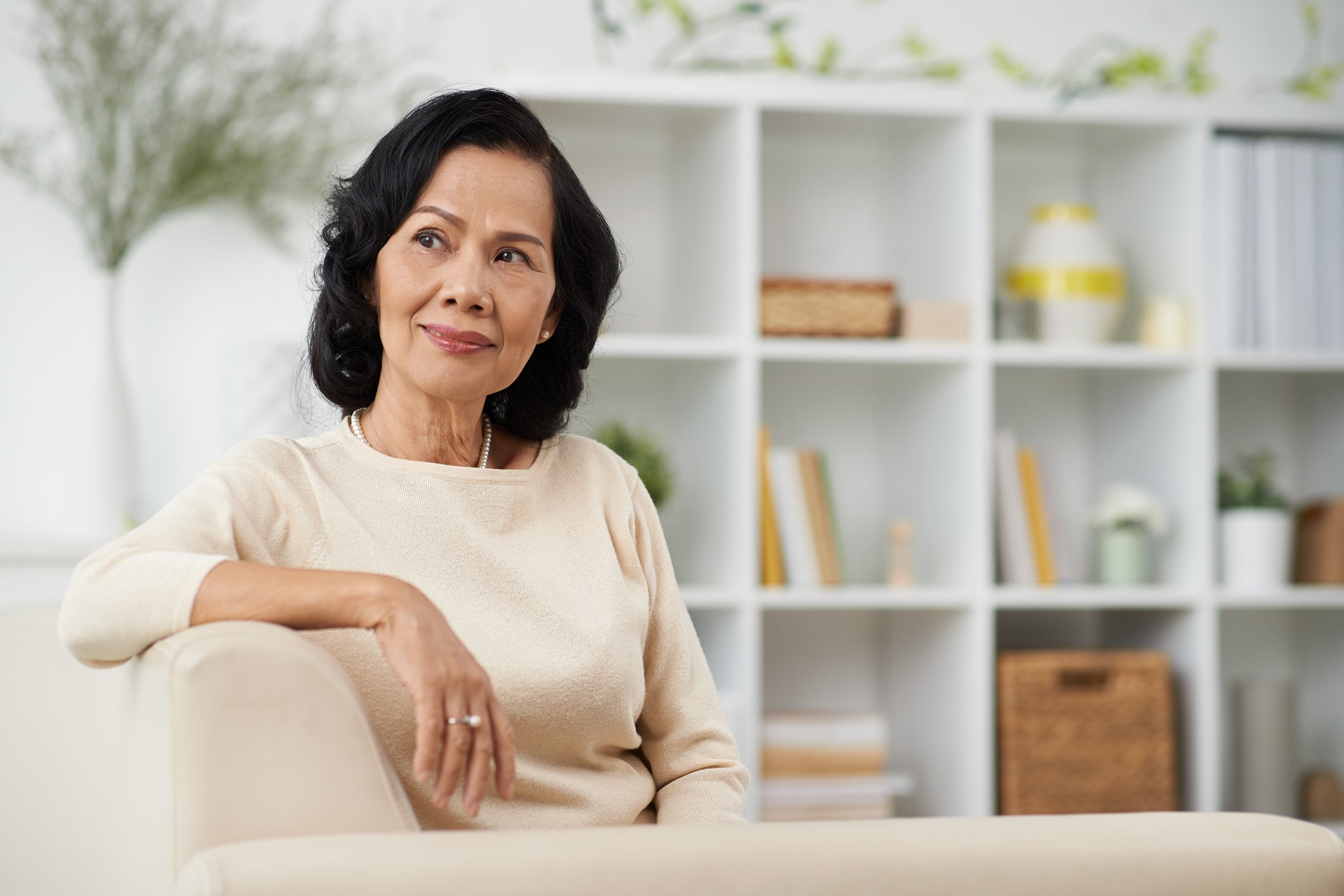 senior woman sitting on couch thinking POC