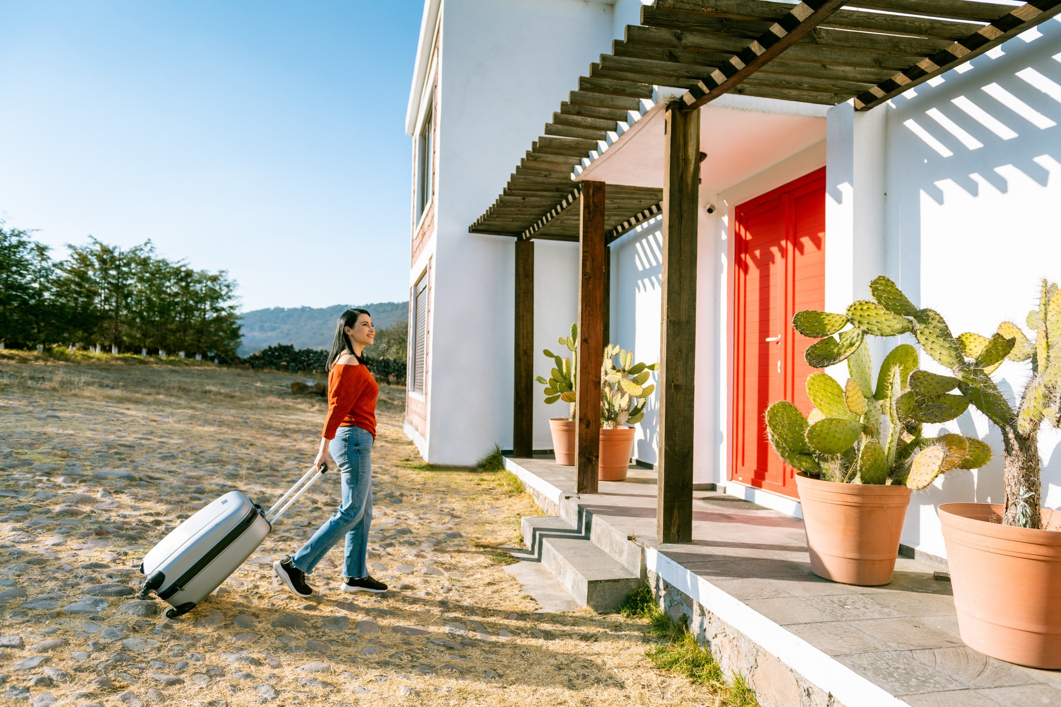 A person with luggage standing outside a house