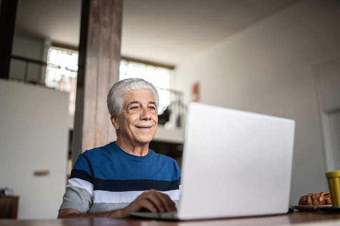 A smiling person at a laptop.