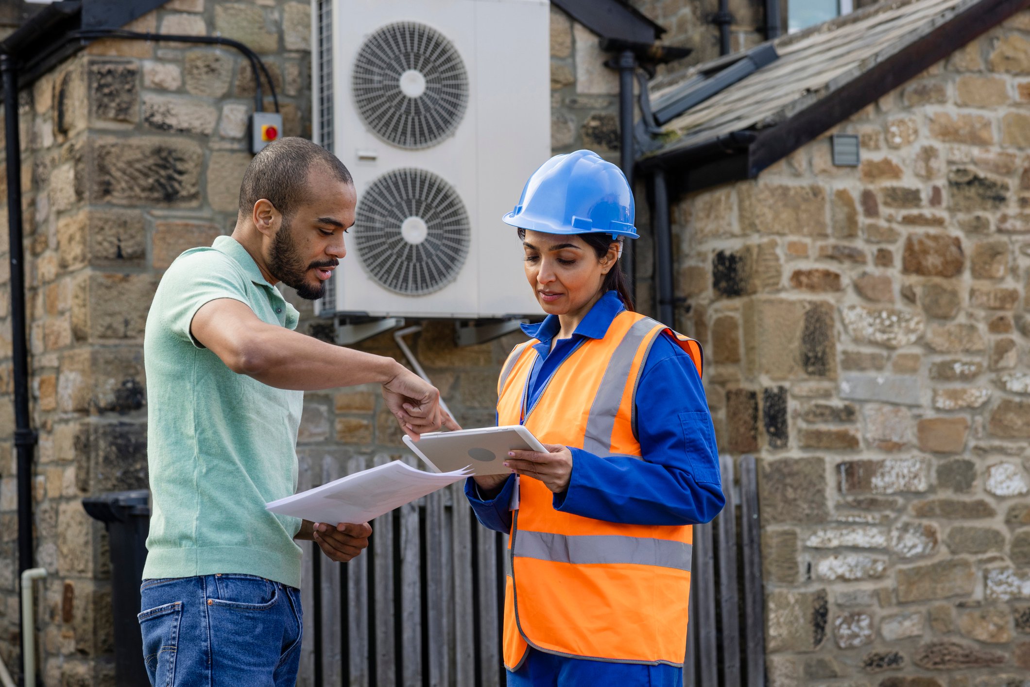 Workers install a heat pump for a building.