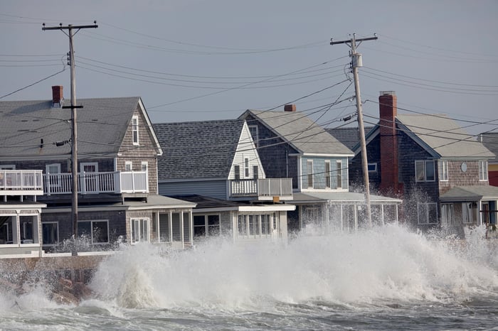 Oceanfront row of houses with waves breaking on seawall.