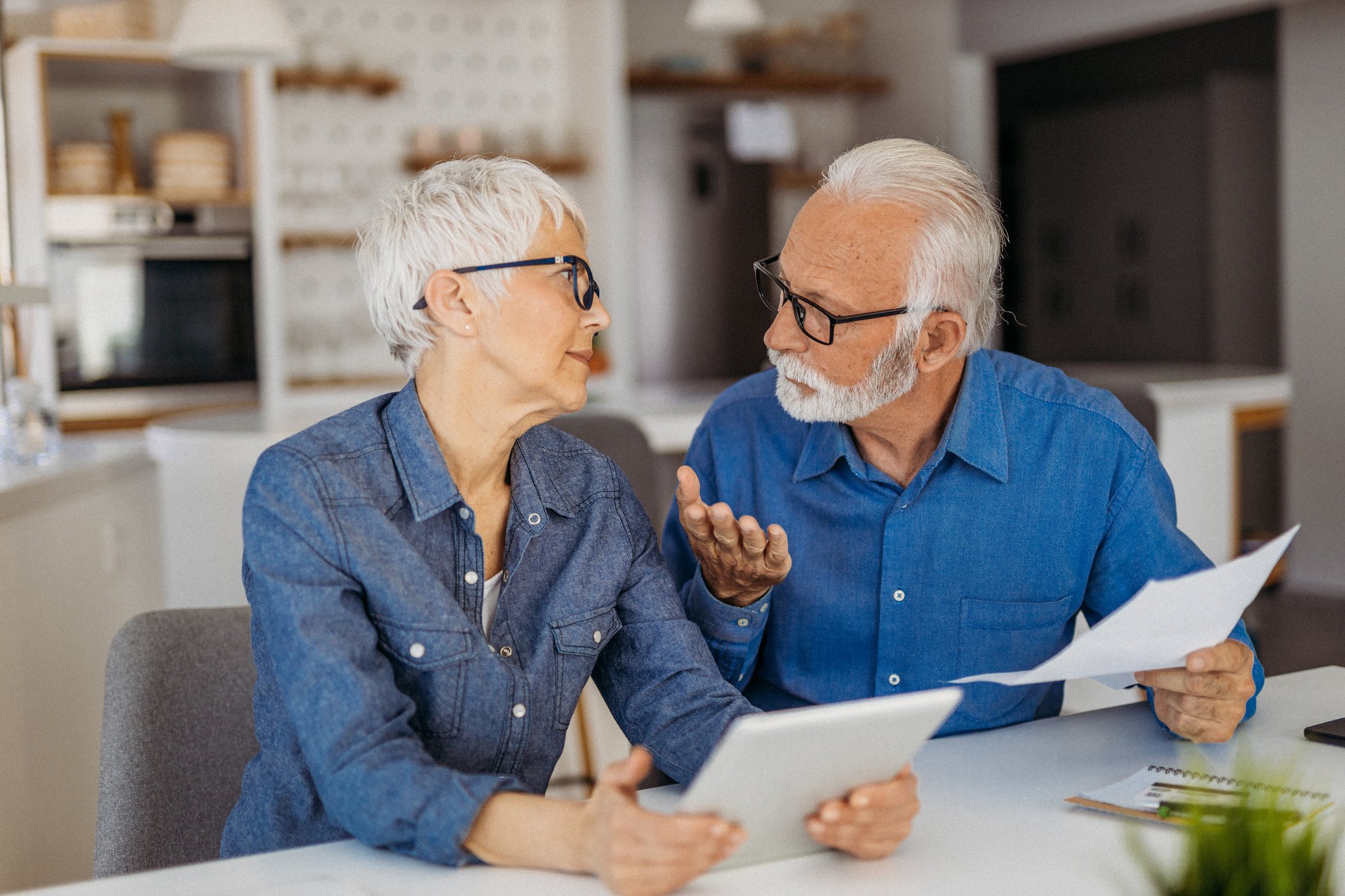 A retired couple talking while holding documents.