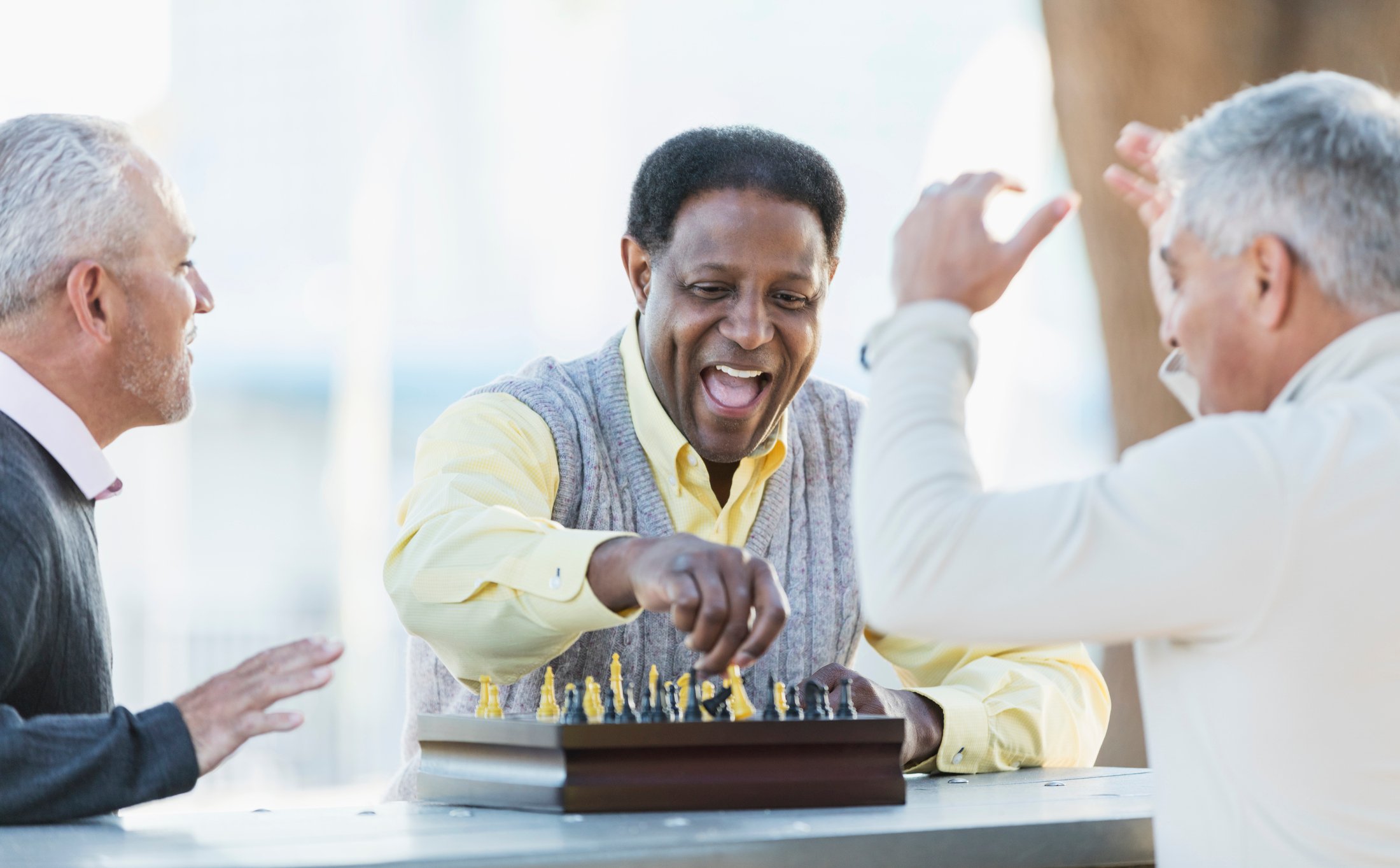 A group of seniors laughing while they play a game of chess.