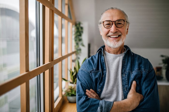 A smiling person next to a set of windows.