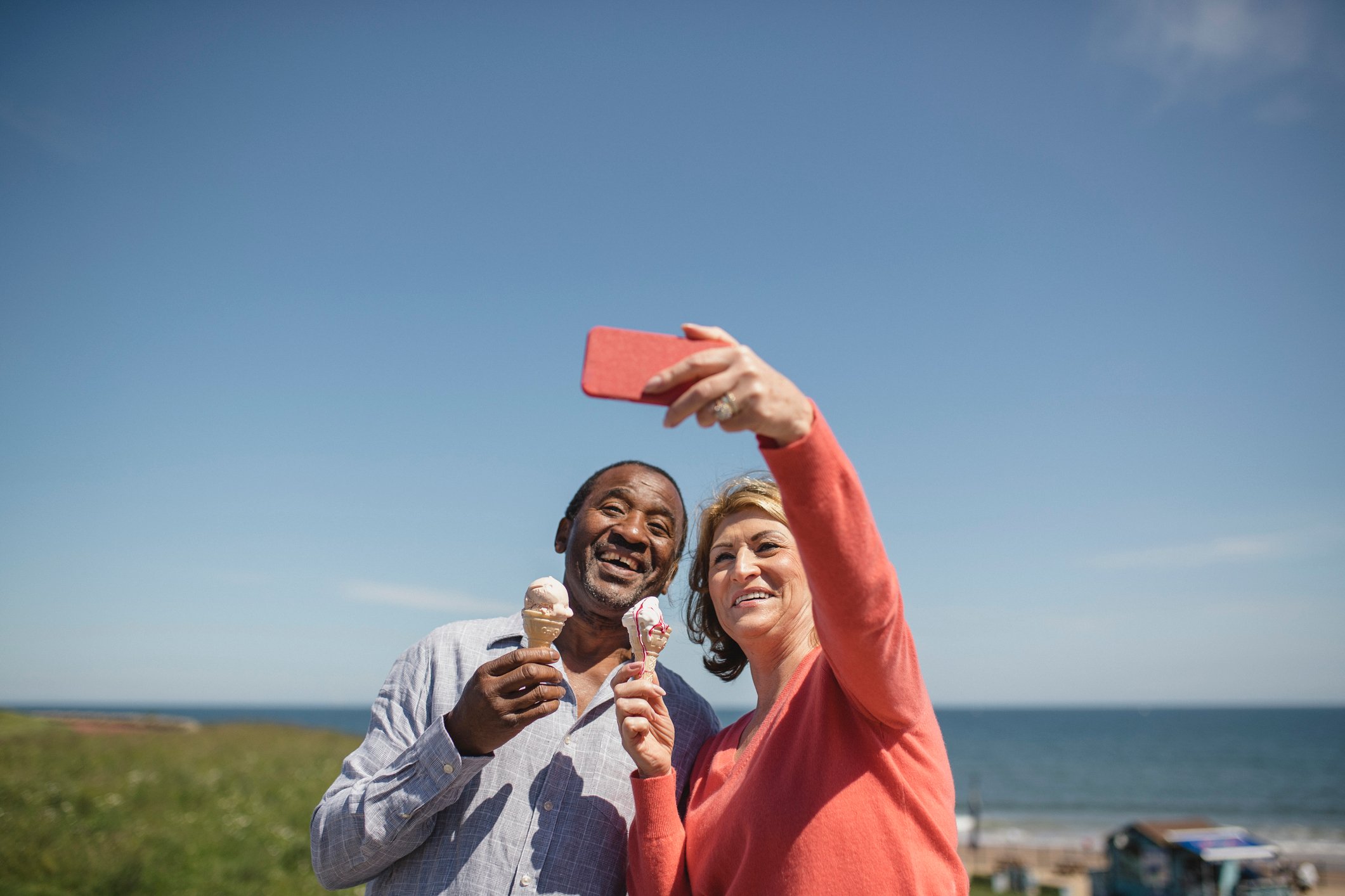 Two people holding ice cream cones and taking a selfie.