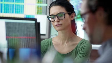 Two business people looking at data on screens.