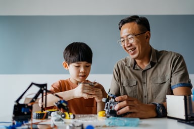 Father and son building robot toy at home