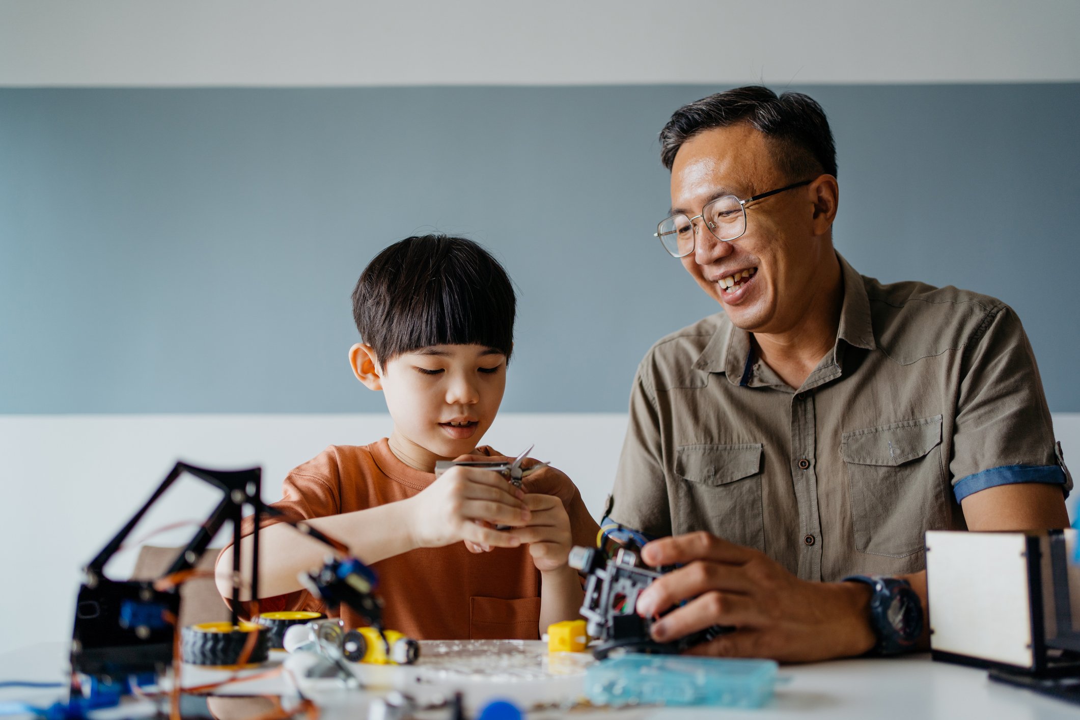 Father and son building robot toy at home
