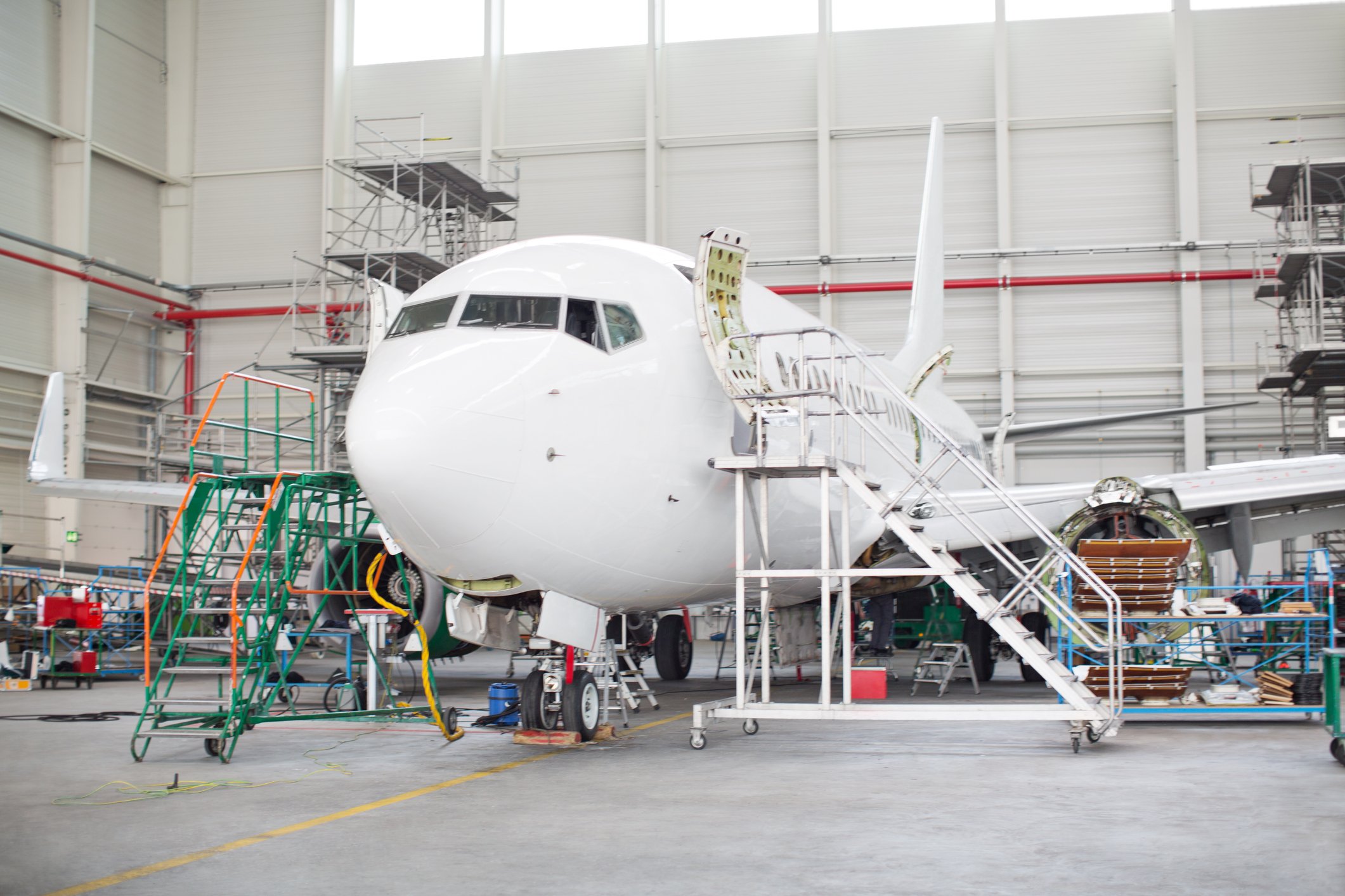 Airplane maintenance with ladders in hangar Getty