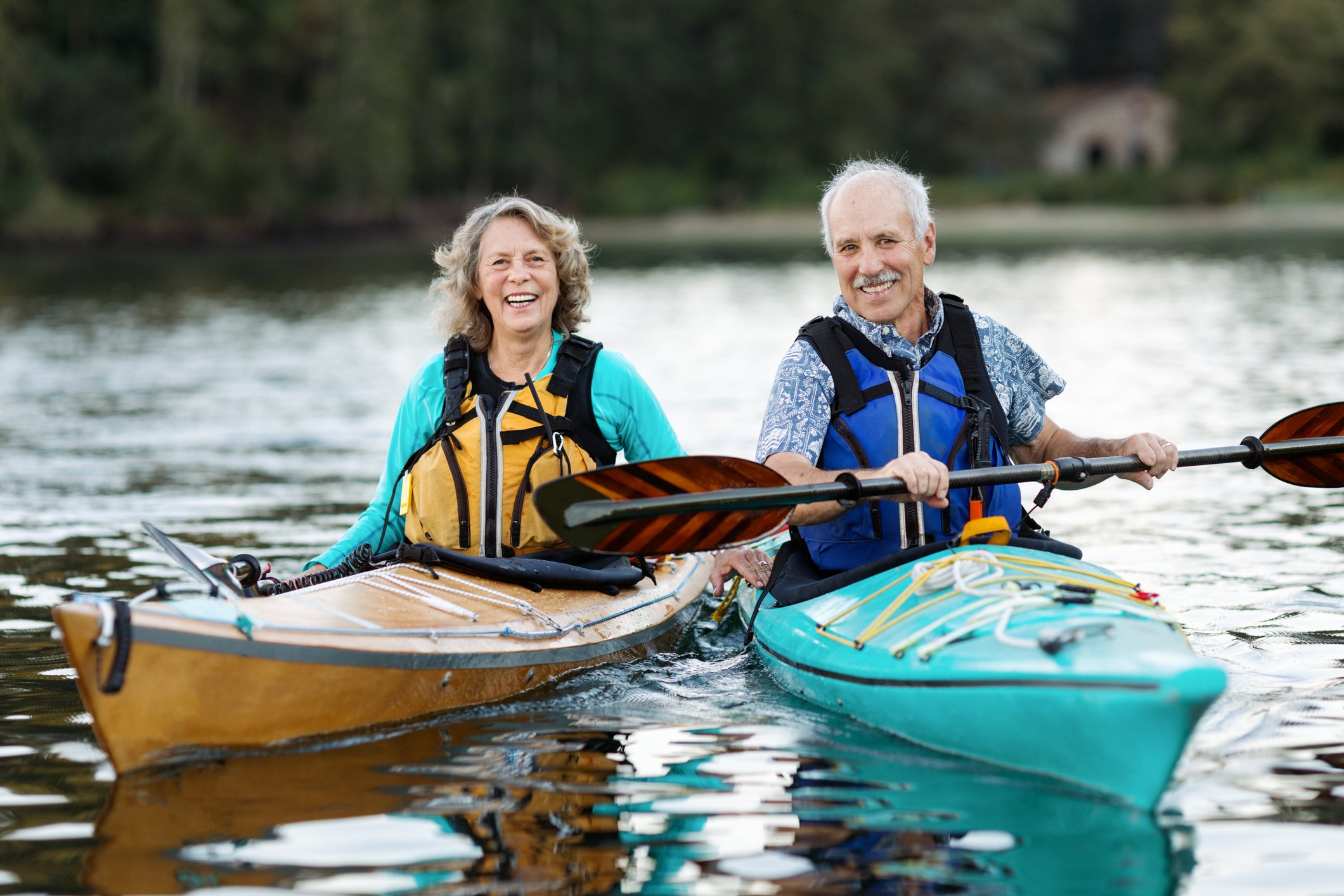 Two people sitting in separate kayaks in a lake.