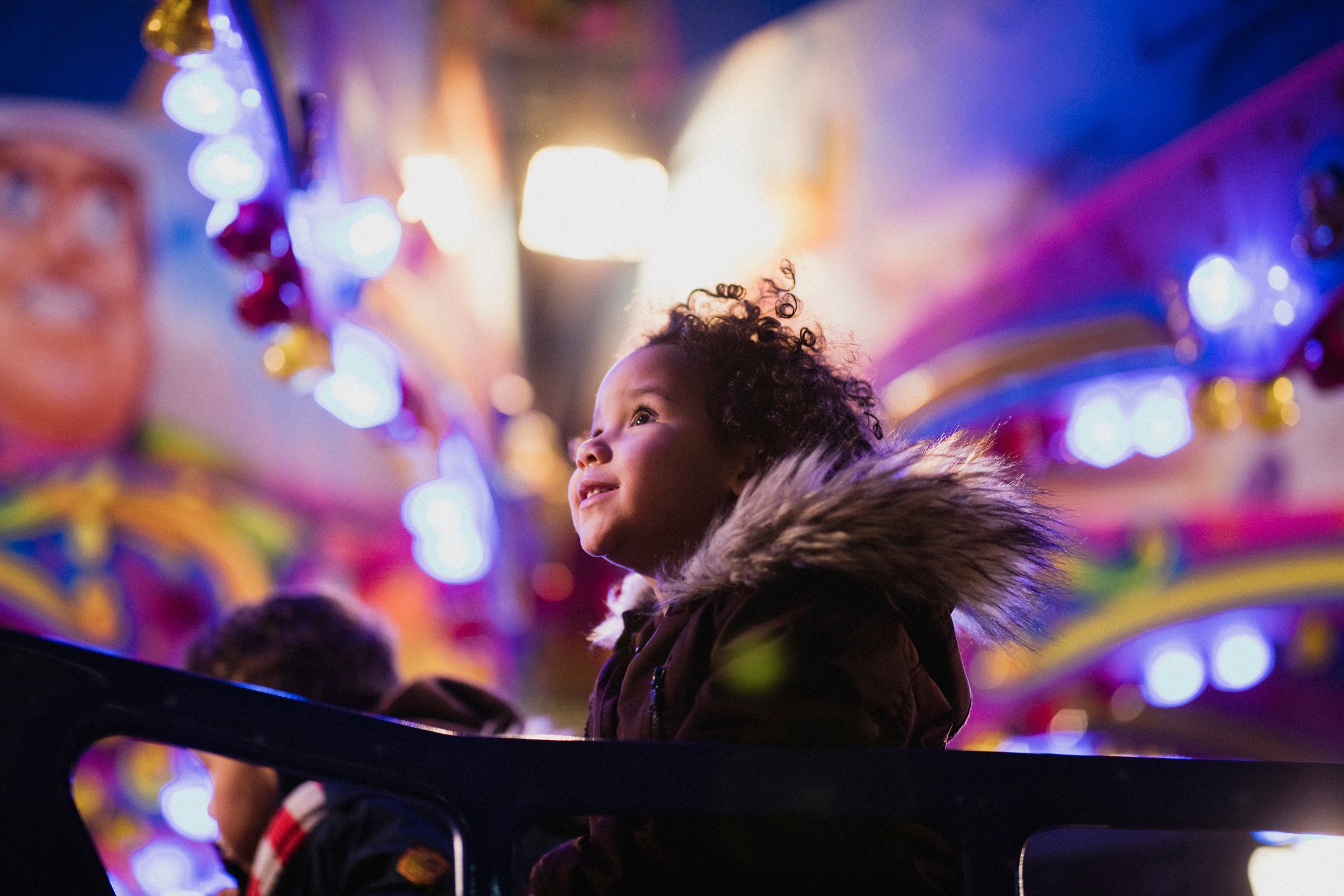 A child looks up and smiles at a theme park.