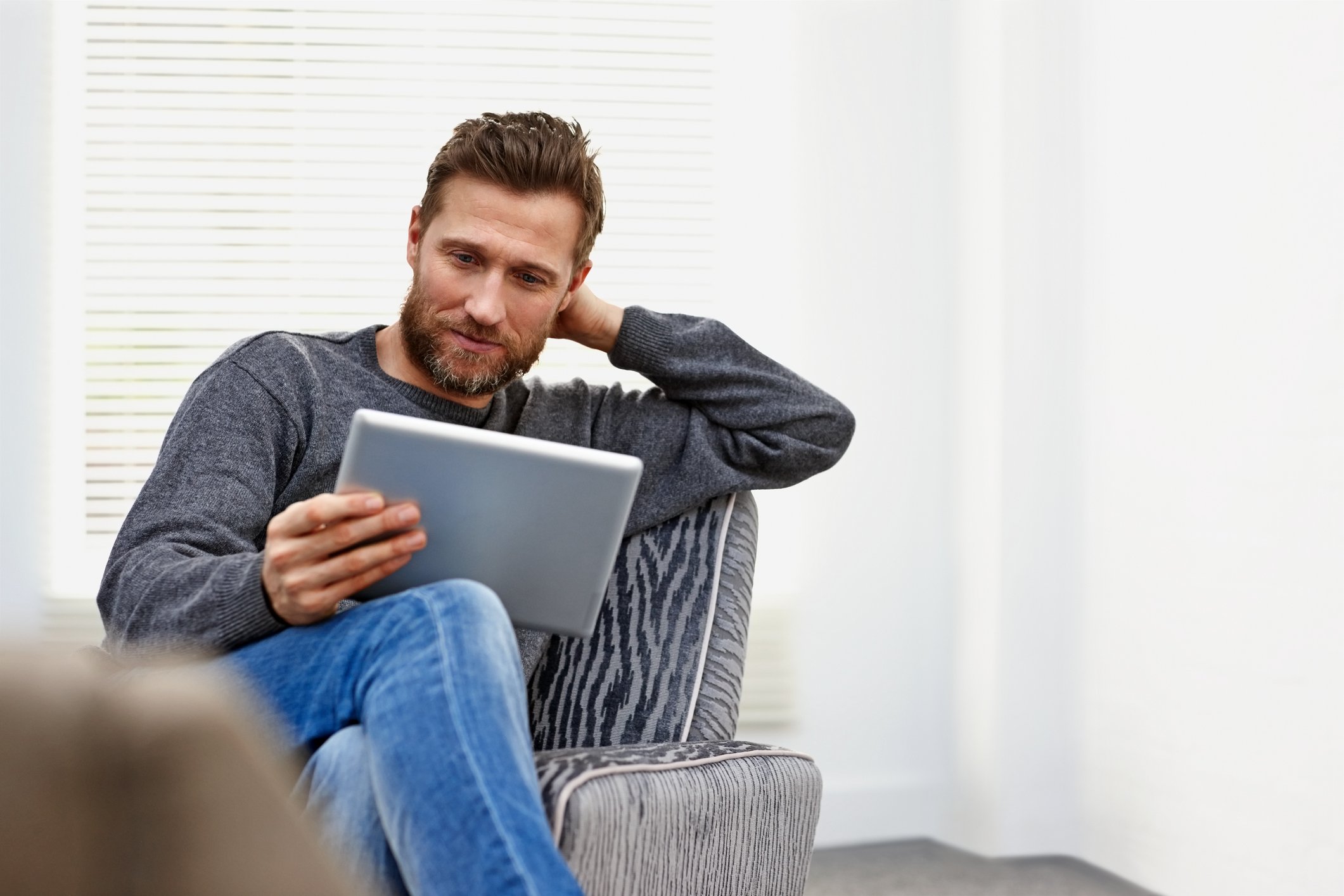 A person looking at a tablet while sitting on a chair.