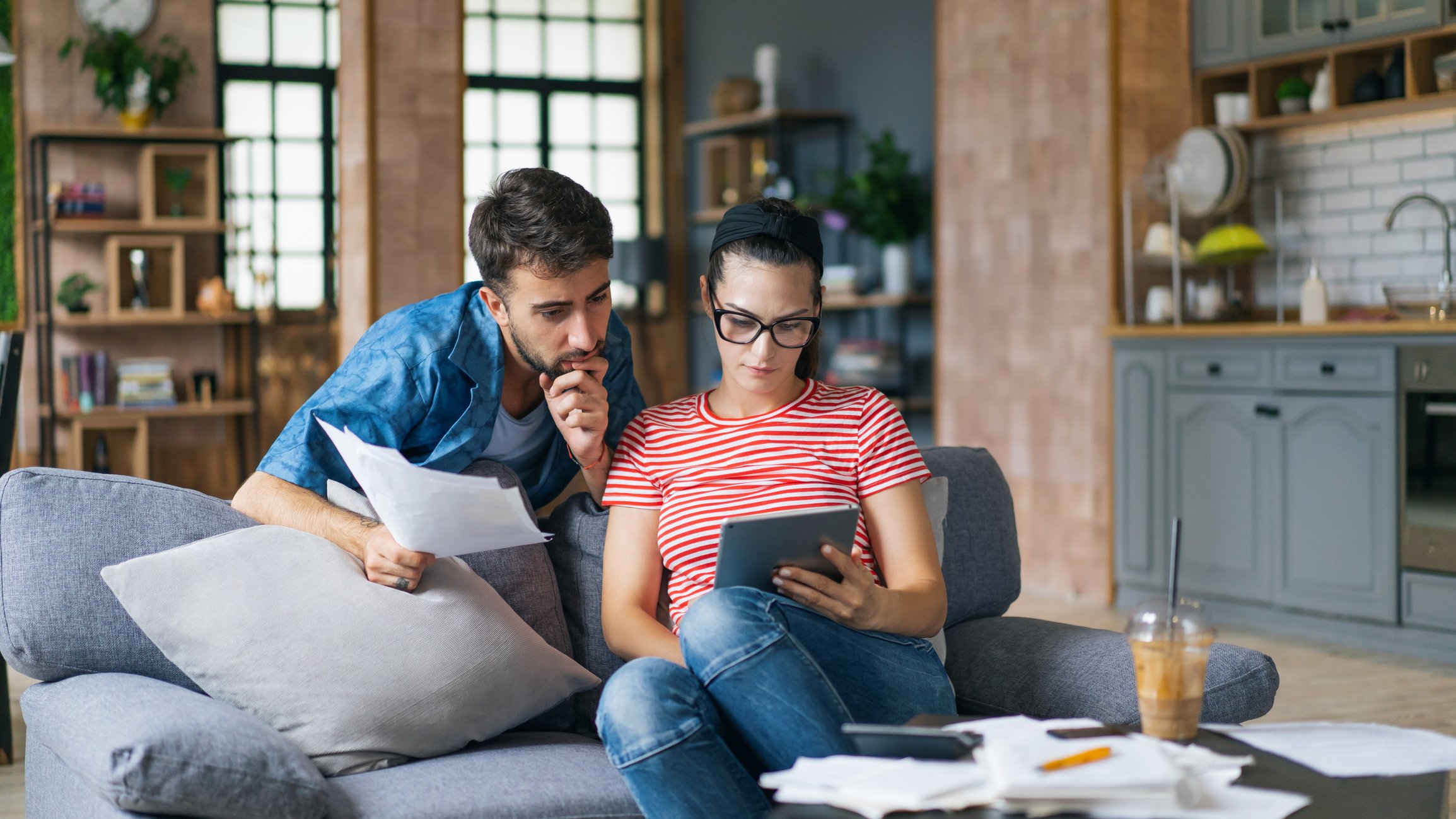 Two people sitting on a couch looking at a tablet.