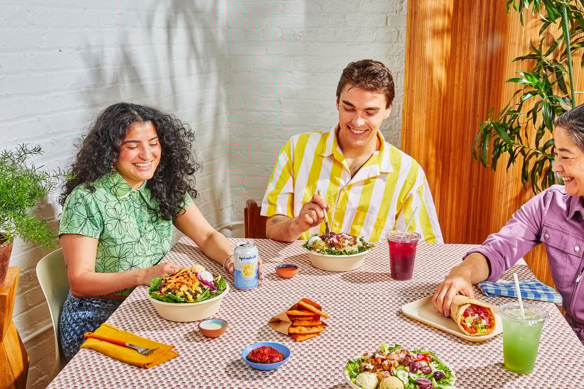 Folks gathering at a table with various Cava takeout offerings.