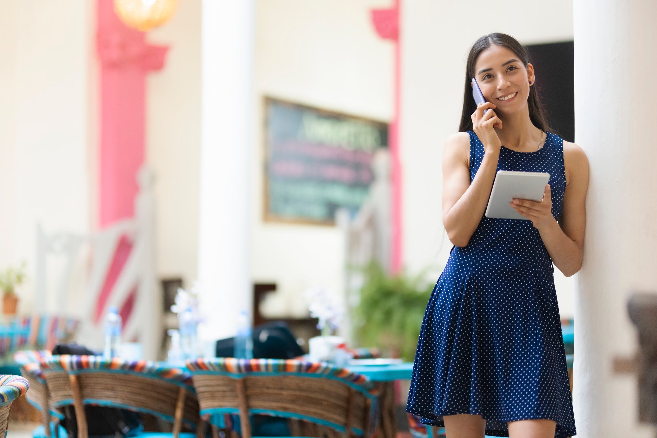 Someone talking on a phone while holding a tablet.