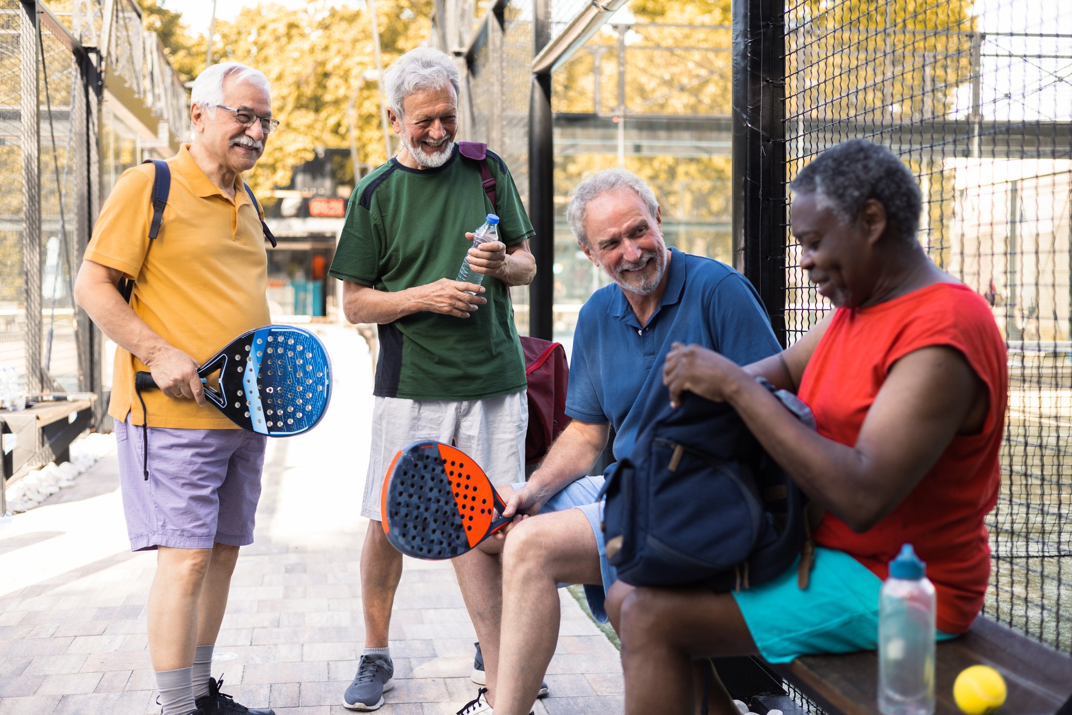 Group of retirees laughing in the park getting ready to play pickleball.