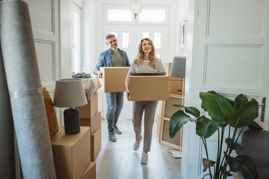 Couple carrying boxes, moving in.