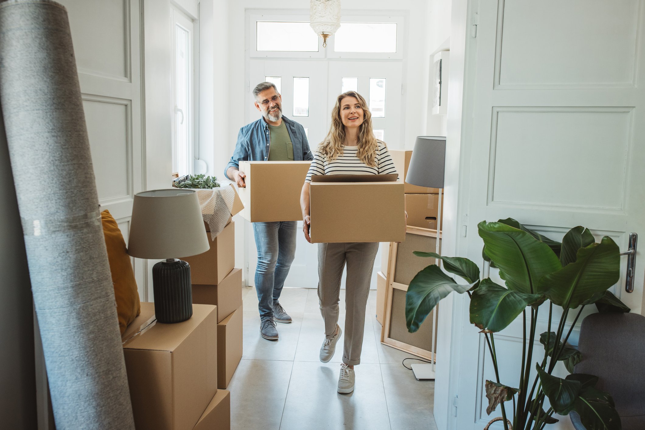 Couple carrying boxes, moving in.