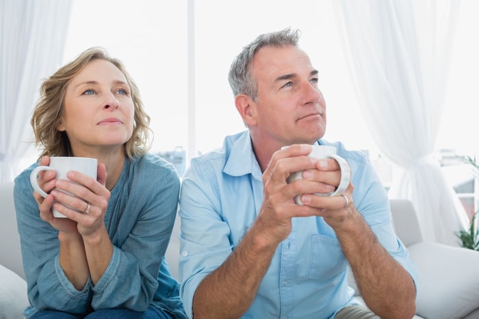 Two people sitting while holding coffee cups.