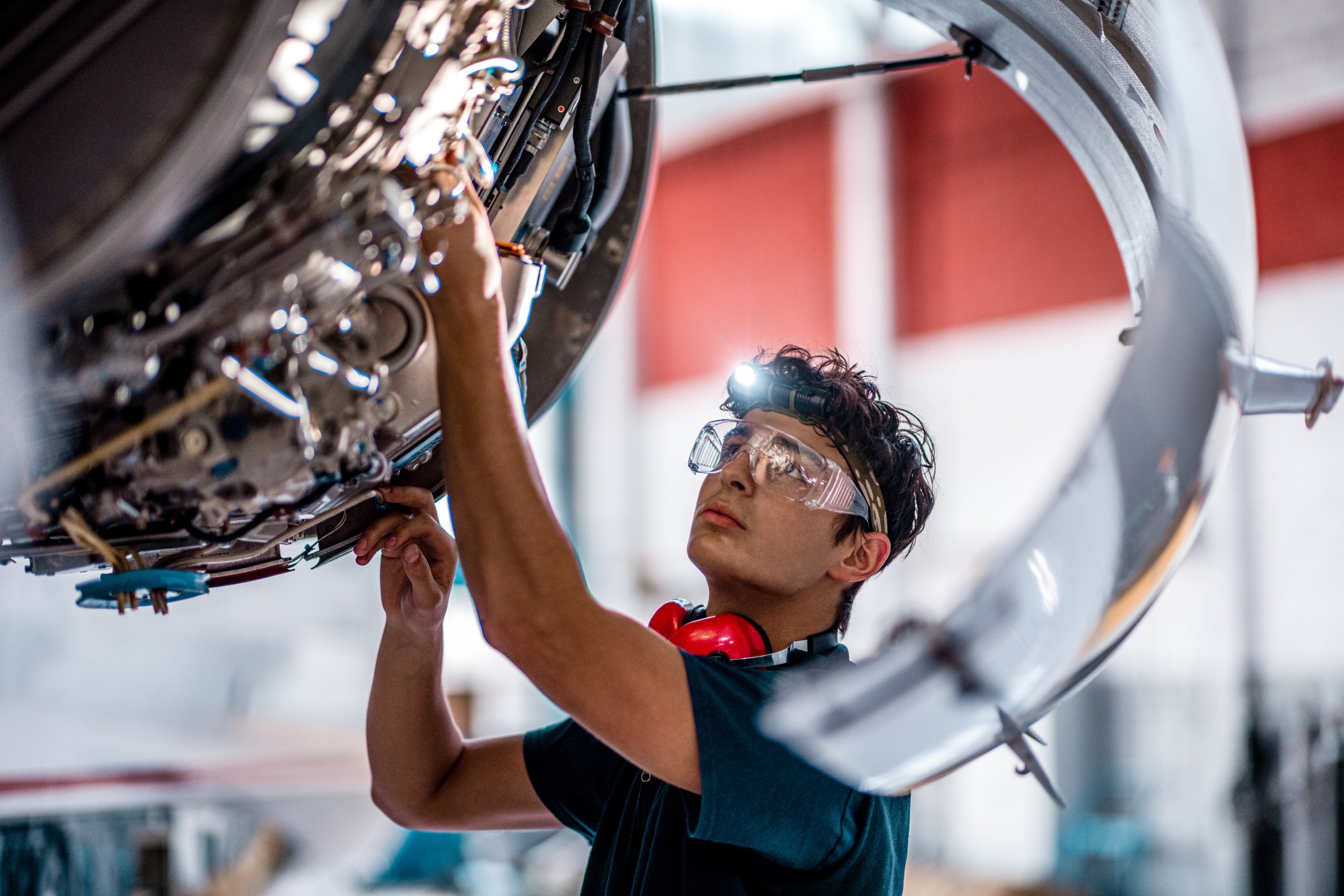 An aircraft mechanic inspects a jet engine.