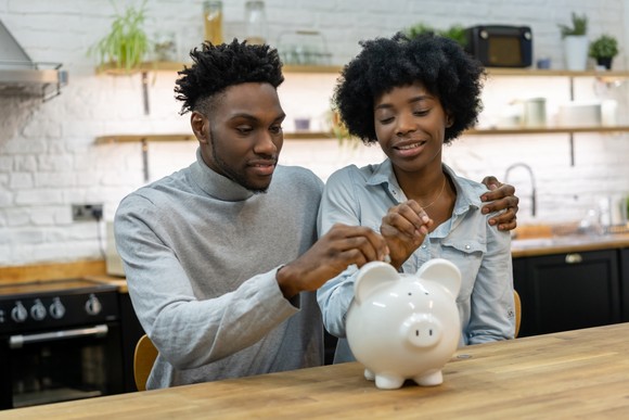 A couple putting money into a piggy bank.