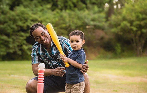 A parent and child play T-ball.