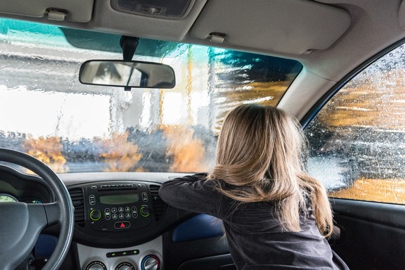 A child looks through the windshield of a car inside a car wash.