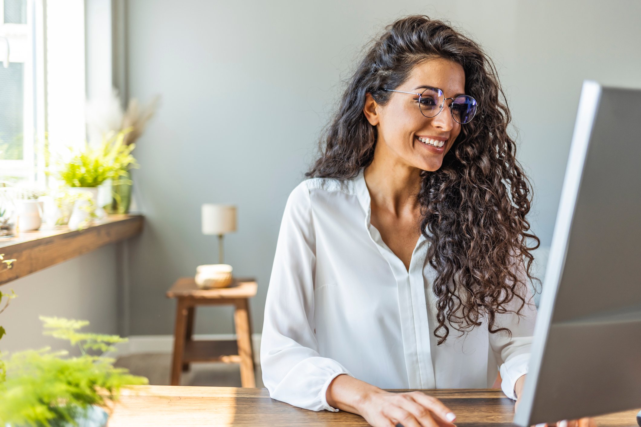 Person smiling and looking at a computer screen.