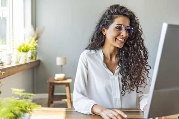 Person smiling and looking at a computer screen.