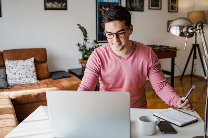 A person at a laptop in a living room setting. 