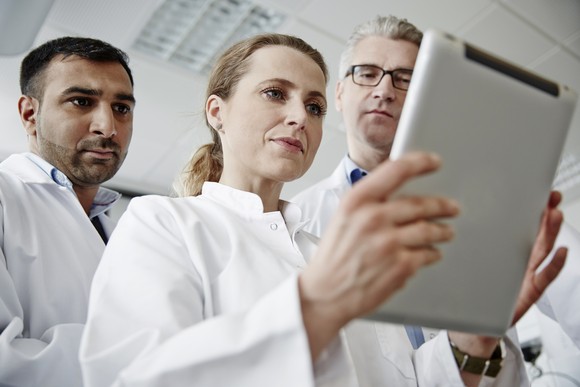 Three scientists looking at a tablet.