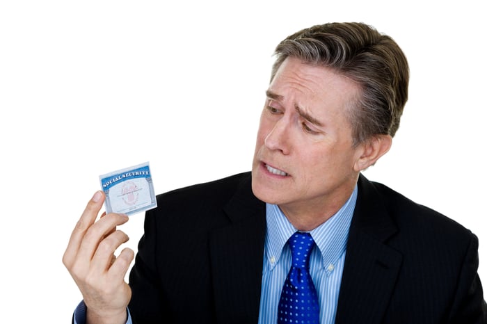 Concerned person wearing a suit and looking frustratingly at a Social Security card.
