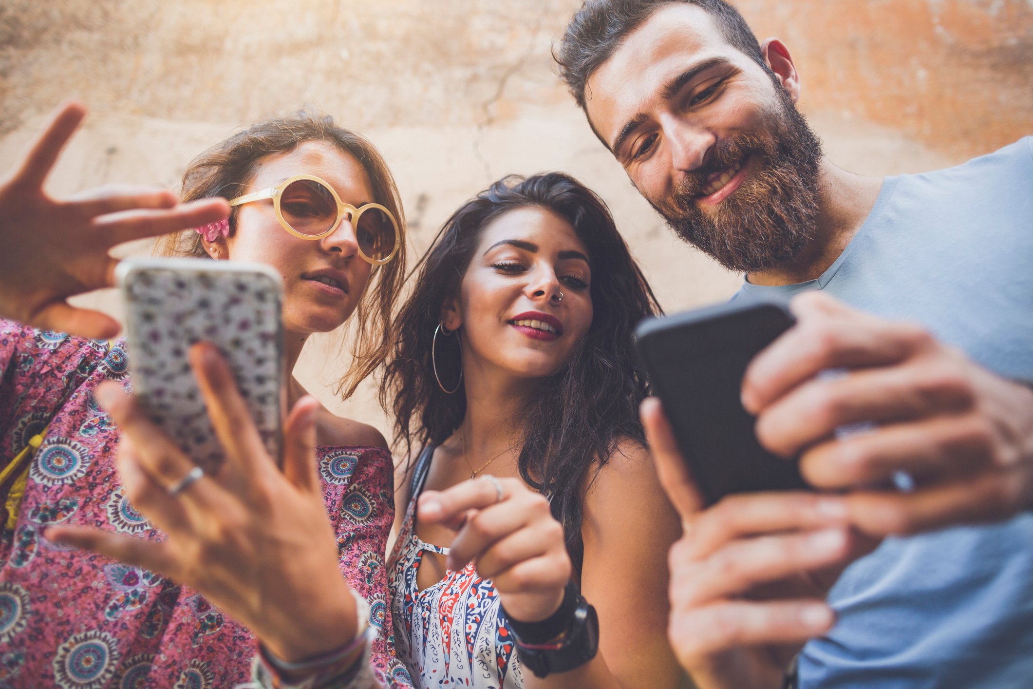 Three friends use their smartphones together.