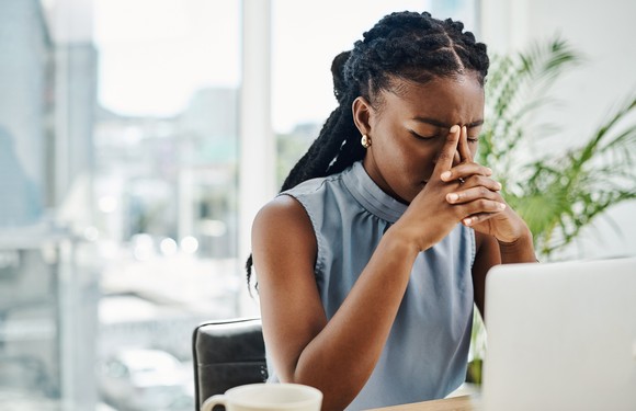 A person with a frustrated look while sitting at a table in front of a computer.