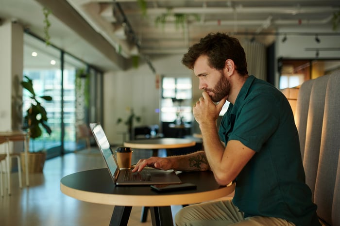 A person at a laptop with a serious expression.