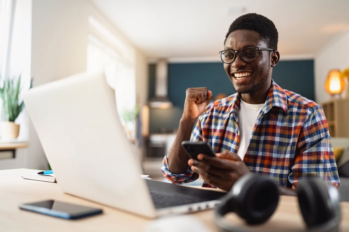 A smiling person at a laptop.
